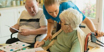 Caregiver assisting elderly couple with coloring