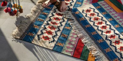 person in blue denim jeans standing on white blue and red area rug